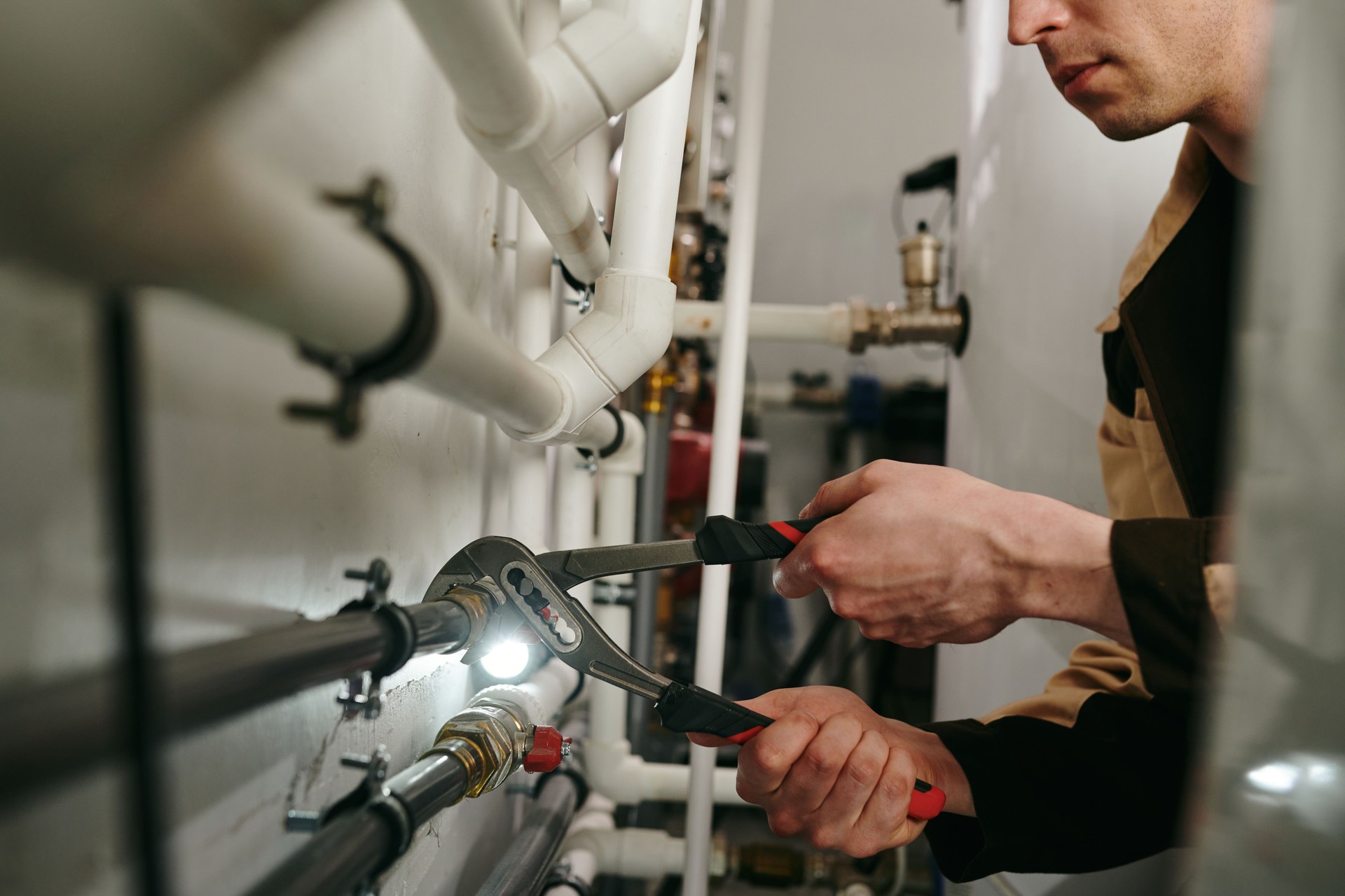 A man using a tool to fix parts of pipes during work